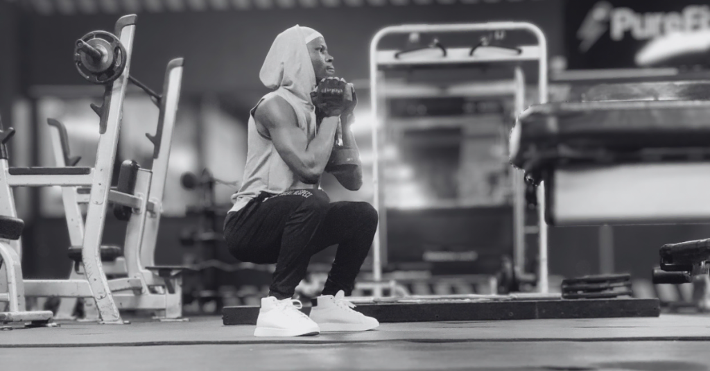 Anthony demonstrating how to do goblet squat with a dumbbell after 30 from a right-side view, showing proper body alignment, squat depth, and dumbbell positioning.