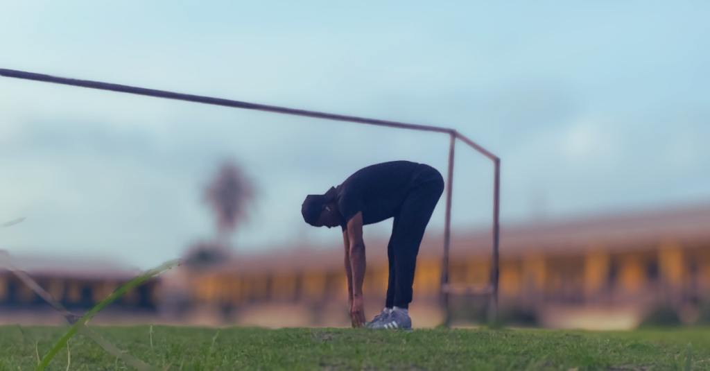 Anthony touching his toes during a stretching exercise showing How to Manage stress After 30 through flexibility work and post-workout recovery movements.