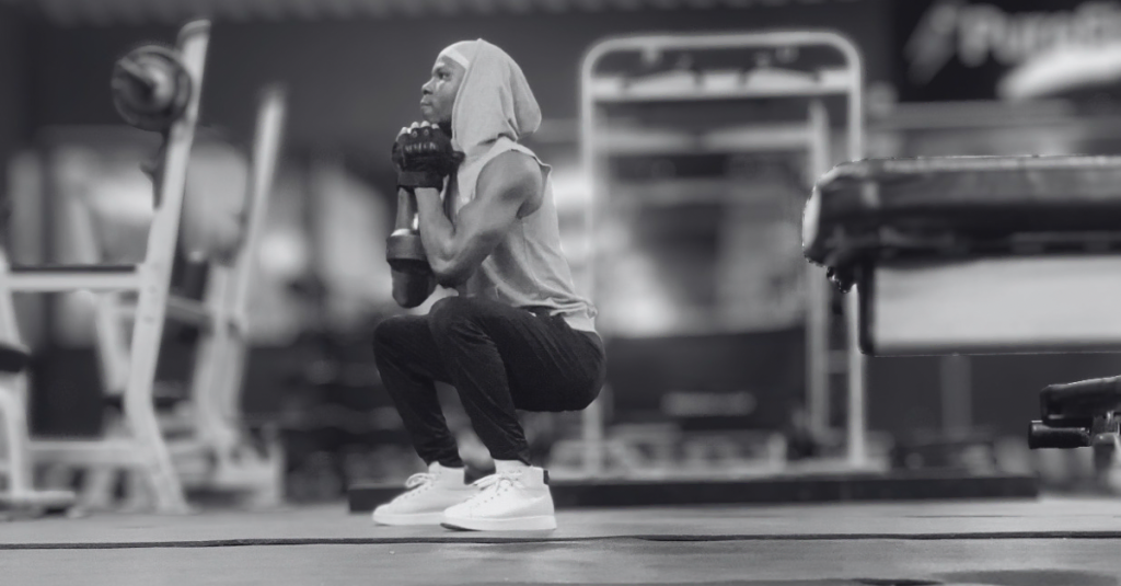 Anthony demonstrating how to do goblet squat with a dumbbell after 30 from a left-side view, showing proper squat depth, posture, and dumbbell positioning.