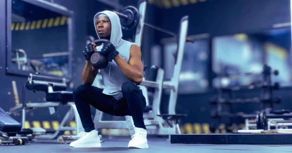 Anthony performing a kettlebell goblet squat from a side view demonstrating goblet squat muscles worked after 30, engaging quads, glutes, hamstrings, and core with proper form and depth.