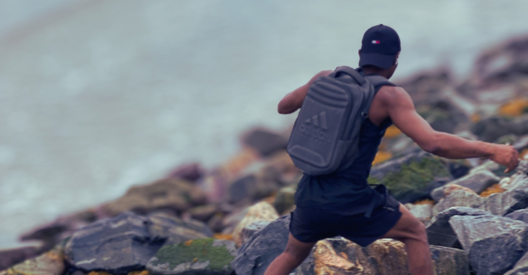 Anthony running on the rocks at the beach side, back shot showing outdoor fitness training. Keyword: How to build a fitness mindset after 30