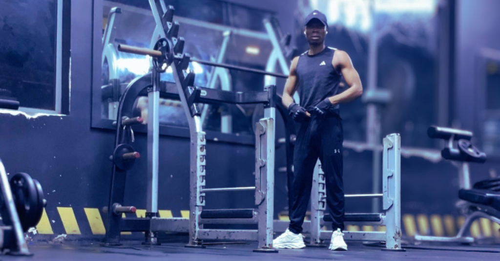 Anthony standing and resting in the gym after training session, taking a break during strength training for recovery and performance.