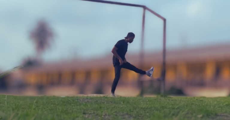 Anthony performing a hamstring stretch in a field while demonstrating that Are Home Workouts Effective After 30 depends on proper recovery, flexibility, and consistent movement.