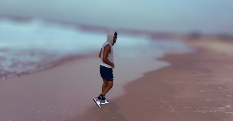 Anthony walking at the beach side reflecting on fitness recovery while demonstrating Why You’re Not Recovering Properly After 30 and the importance of active recovery and stress reduction.