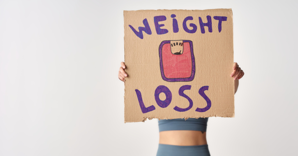 Woman holding a placard with weight loss motivation text, representing how to track weight loss after 30 and stay consistent with fitness goals.