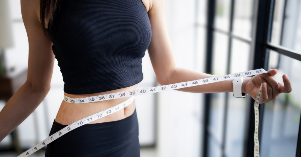 A lady measuring her waist with a tape measure, showing how to track weight loss after 30 using body measurements to monitor progress.