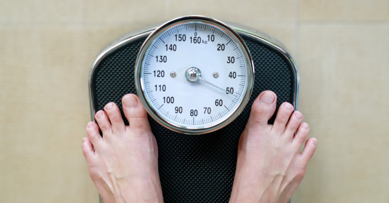 Someone standing on a weighing scale checking their progress, illustrating how to track weight loss after 30 as part of a fitness journey.