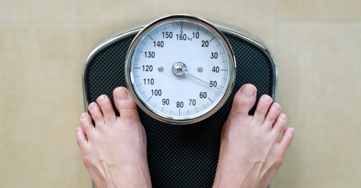 Someone standing on a weighing scale checking their progress, illustrating how to track weight loss after 30 as part of a fitness journey.