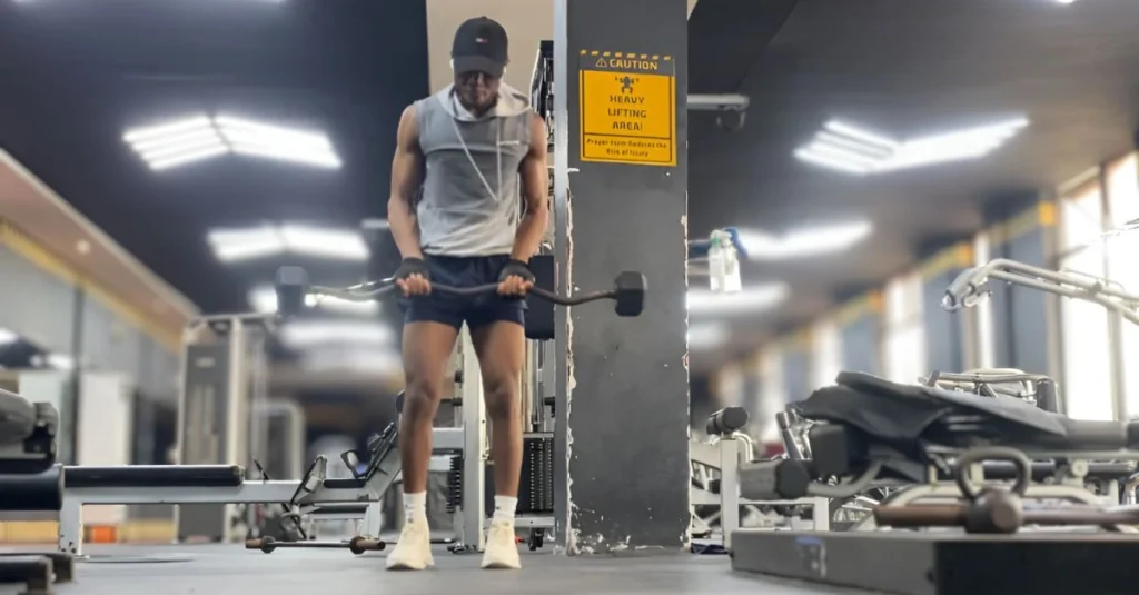 Fitness After 30: Anthony standing in the gym holding an EZ bar during a strength training session.