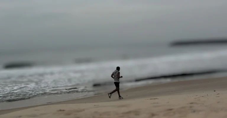 Weight Loss After 30: Anthony jogging along the beach from the opposite direction as part of a cardio fat loss routine.