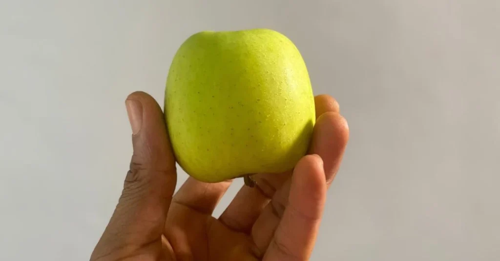 Nutrition After 30: A hand holding a fresh green apple as a healthy snack choice for balanced nutrition and wellness.