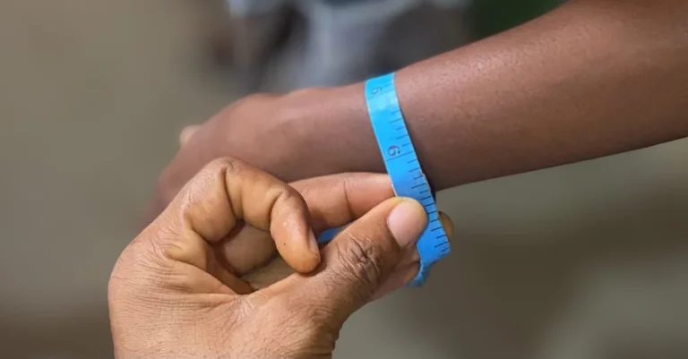 Anthony measuring a woman’s wrist with a tape to learn how to track weight loss