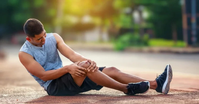 Man holding his knee while sitting on the floor for recovery tips