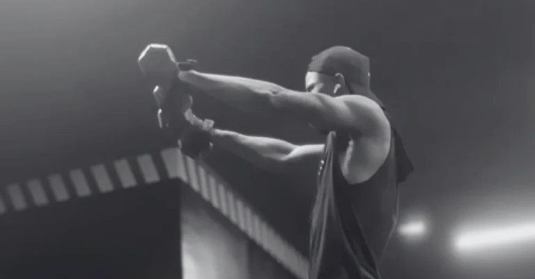 Anthony is performing front raises with dumbbells using proper form during a shoulder workout