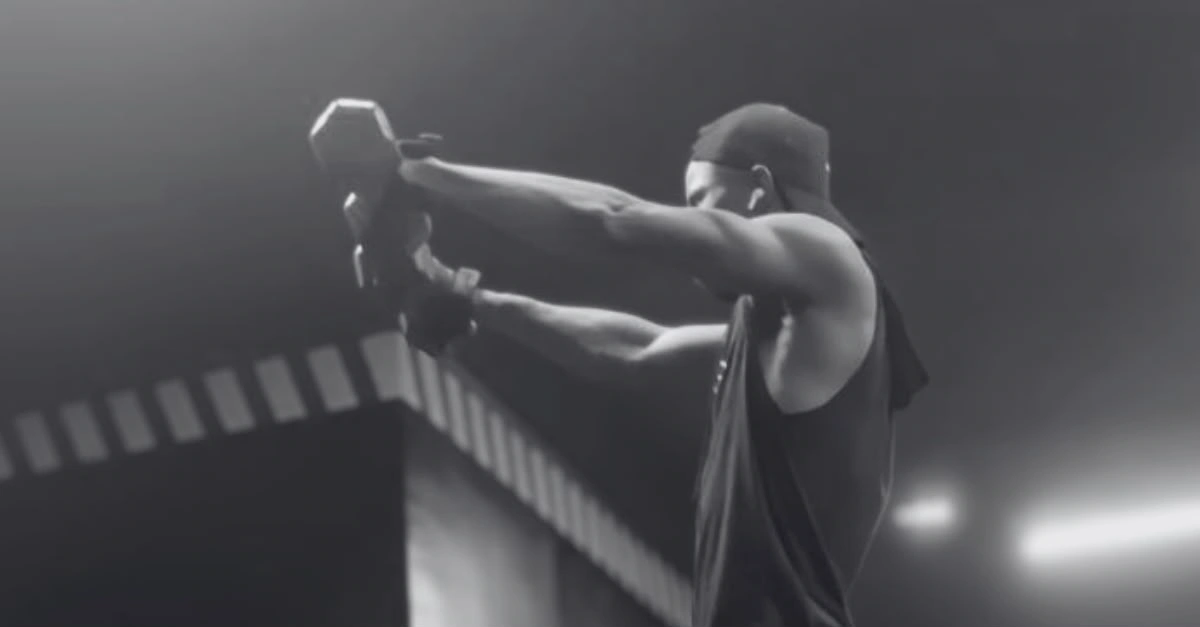Anthony is performing front raises with dumbbells using proper form during a shoulder workout