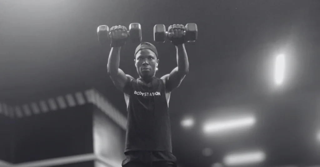 Front view of Anthony performing front raises with dumbbells using proper shoulder exercise form
