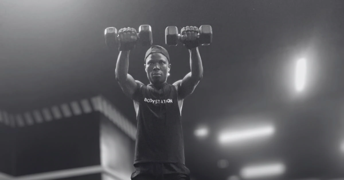 Anthony is performing dumbbell front raises as part of a full shoulder workout with dumbbells to strengthen the front deltoids