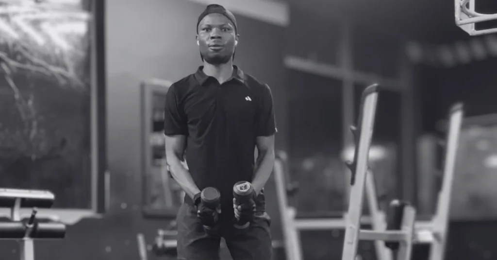 Anthony is preparing to perform dumbbell lateral raises with proper starting position and posture