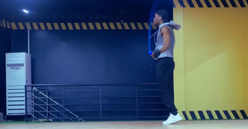 Side view of Anthony performing a jump rope exercise with proper form during a cardio workout.