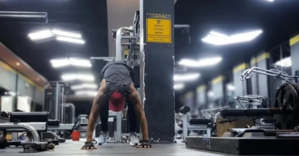 Anthony performing the tuck phase of a burpee exercise by driving his knees toward his chest.