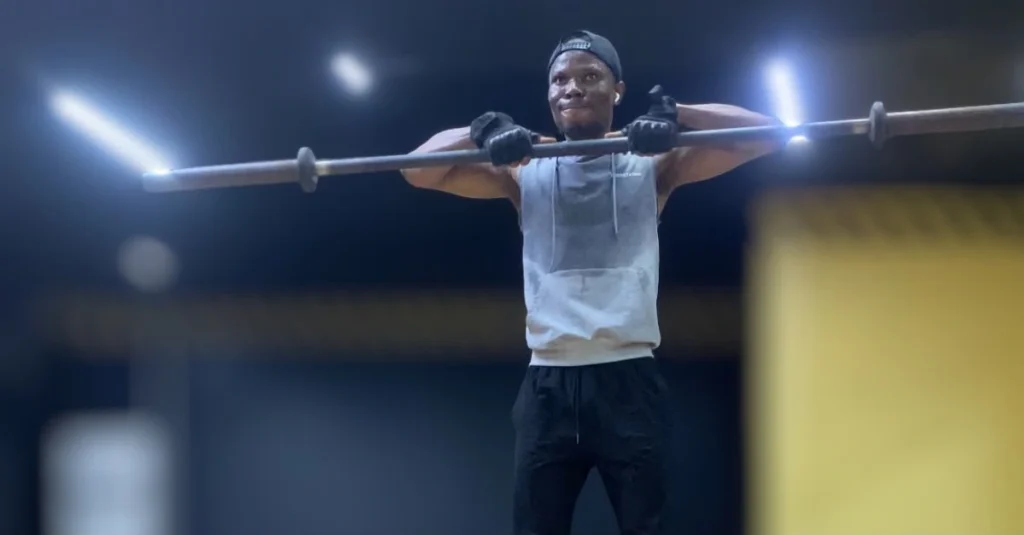Anthony performing a barbell upright row from a front view, demonstrating proper exercise form.