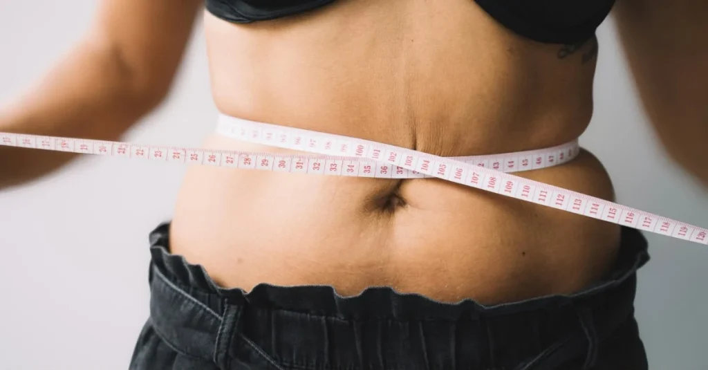 Woman measuring her waist with a measuring tape