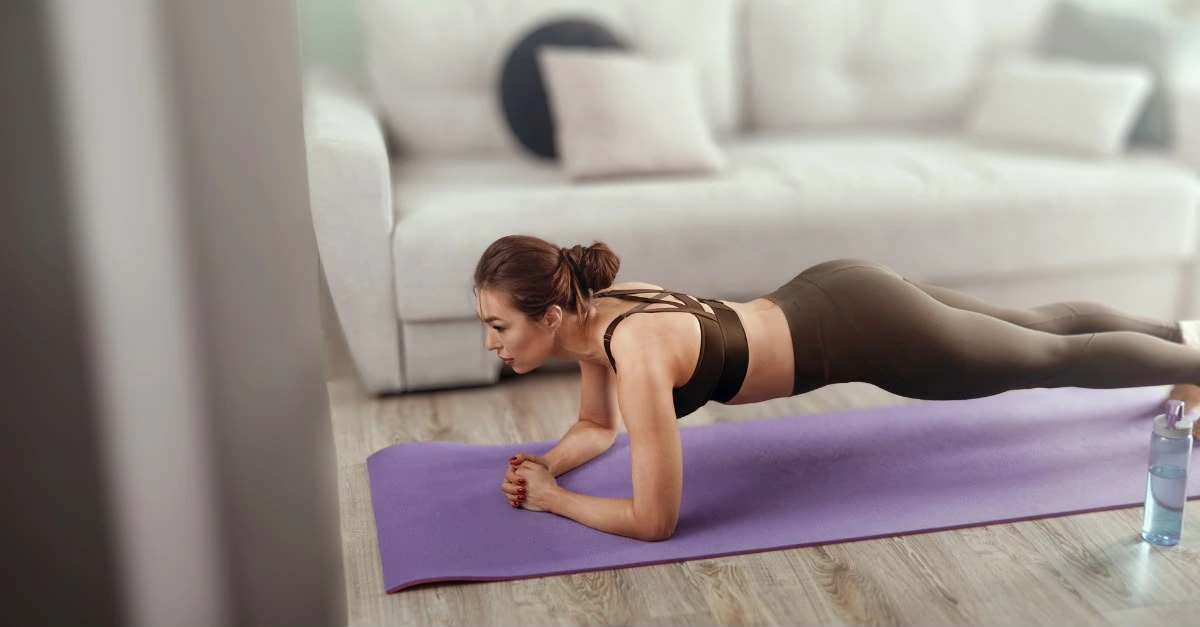 A woman performing a plank exercise in her living room as part of her home workouts.
