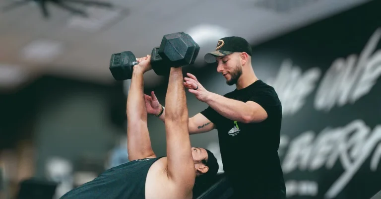 Trainer helping a client perform a dumbbell press during strength training